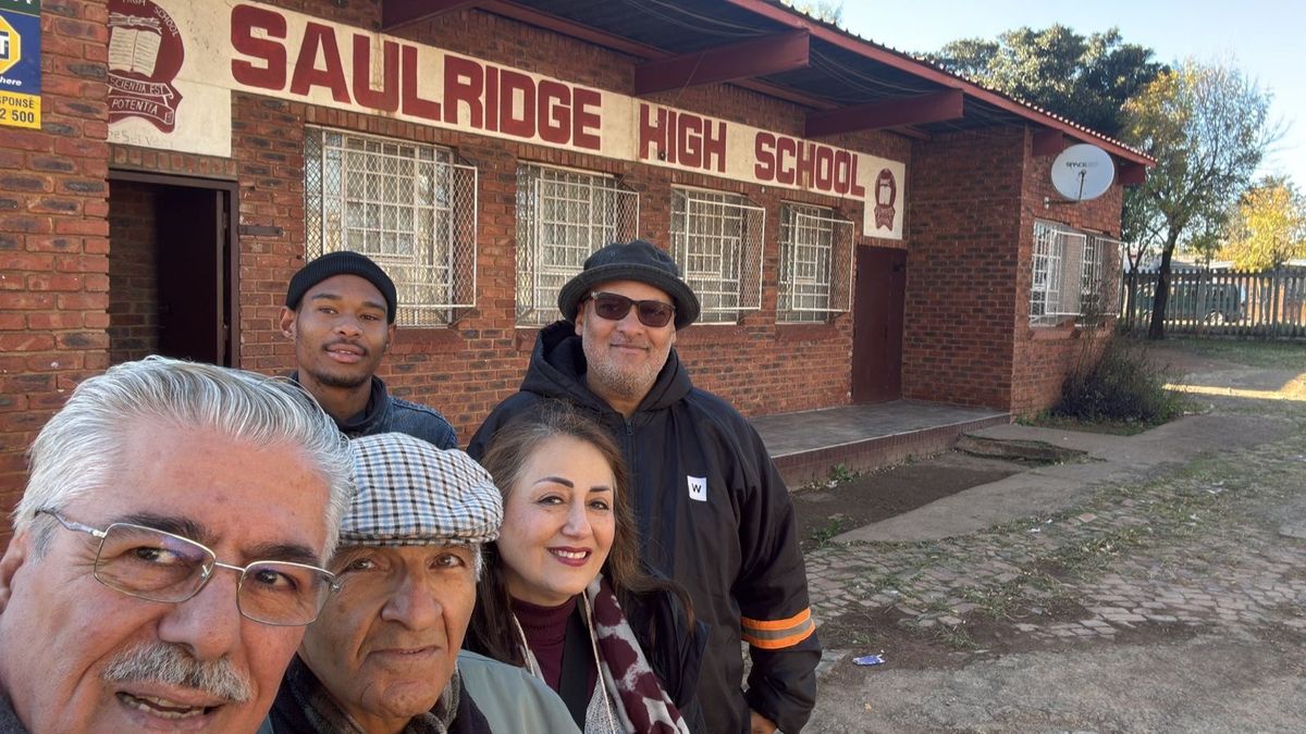 Members of the Mona With The Children team standing together outside a school
