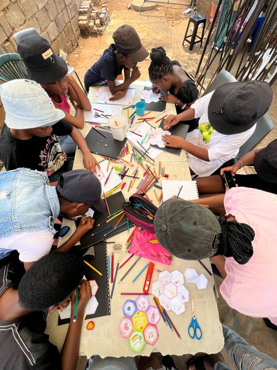 Junior youth colouring hexagonal artwork tiles around a table